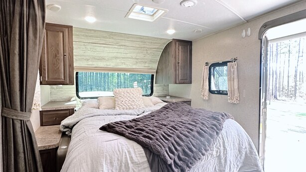 A bedroom with a bed, a window, a vanity, and a ceiling light. - Joy ~ The Happy Little Camper (Loranger)