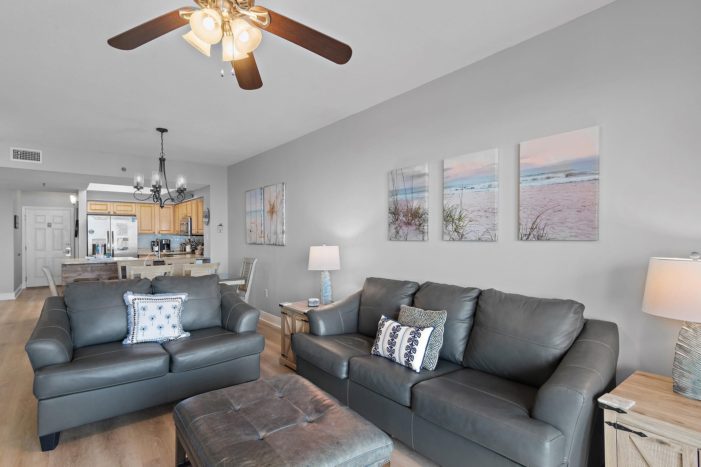 A modern living room with a gray leather sofa set, a wooden coffee table, and a ceiling fan.
