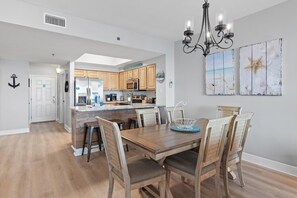 A modern kitchen with wooden cabinets, a central island, and a dining area with a wooden table and chairs.