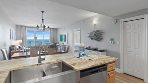 Une cuisine moderne dotée d’un grand îlot central, d’appareils électroménagers en acier inoxydable et offrant une vue sur l’océan.