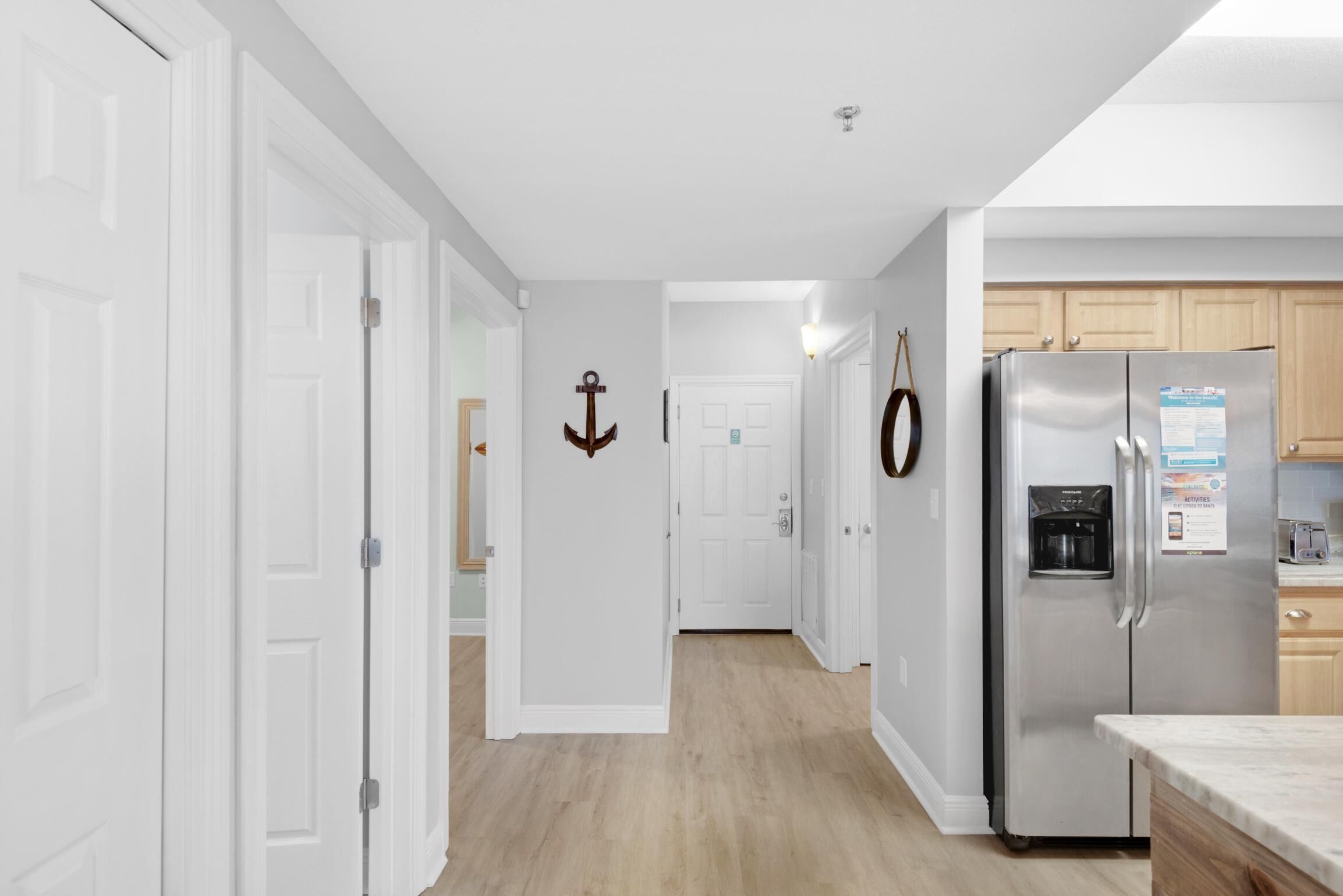 A modern kitchen with white cabinetry, a stainless steel refrigerator, and a wooden floor.
