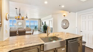 A modern kitchen with a granite countertop, stainless steel sink, and built-in dishwasher. - Ariel Dunes II 1601 (Miramar Beach)