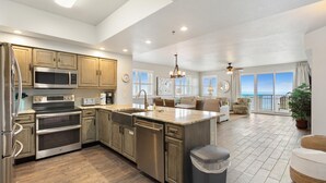 A spacious kitchen with modern appliances, a large island, and a view of the ocean. - Ariel Dunes II 1601 (Miramar Beach)