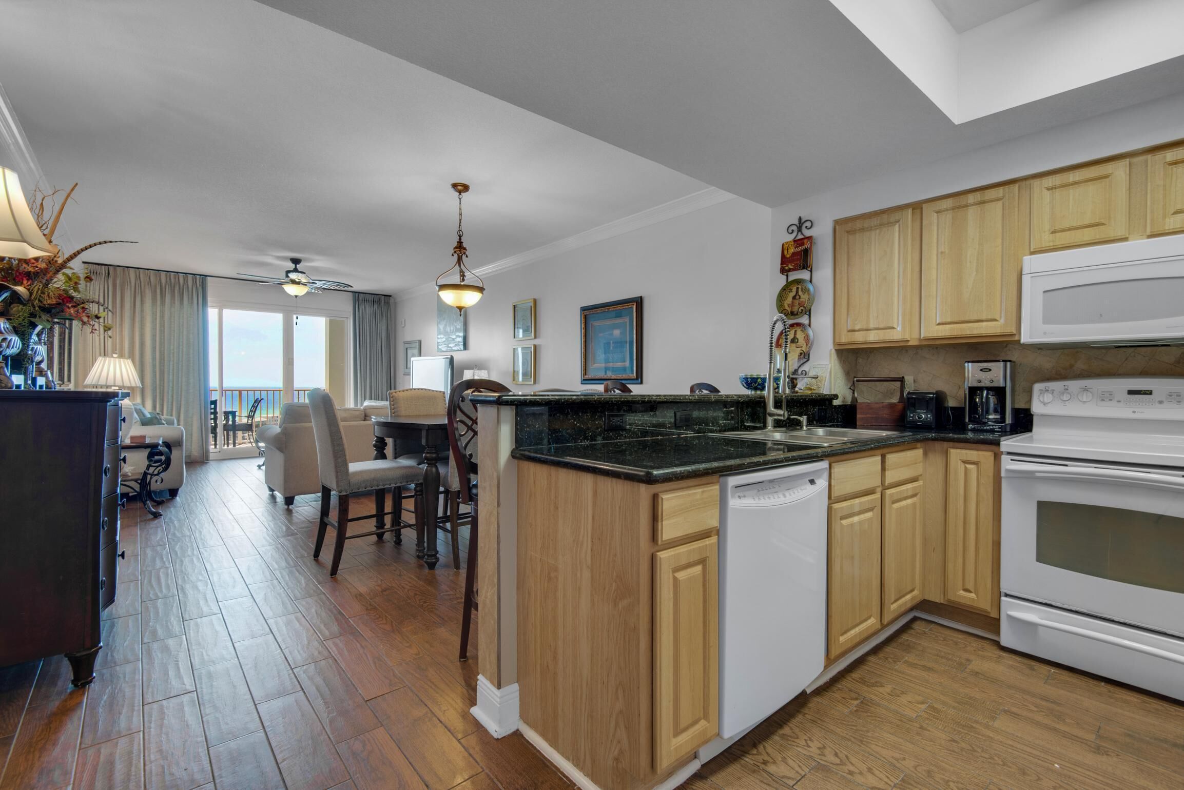 A modern kitchen with wooden cabinets, a central island, and a dining area with a view.