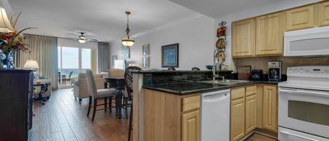 A modern kitchen with wooden cabinets, a central island, and a dining area with a view.