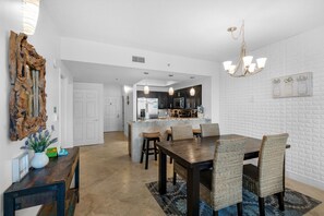 Une cuisine moderne avec des meubles de couleur sombre, un îlot central et des luminaires suspendus.