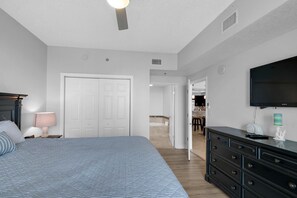 Une chambre à coucher comprenant un lit, une commode, un téléviseur et une porte donnant sur une salle de bain.
