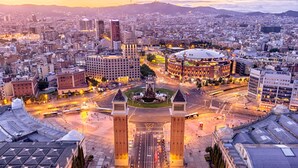 Un paisaje urbano con un edificio circular destacado, un monumento central y arquitectura moderna circundante.