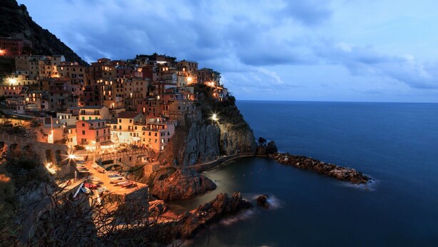 Un pueblo costero con edificios a lo largo del acantilado, una costa rocosa y un mar tranquilo.