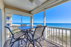 A covered patio with a table and chairs, overlooking a beach. - Riviera Dunes 501 (Pensacola)