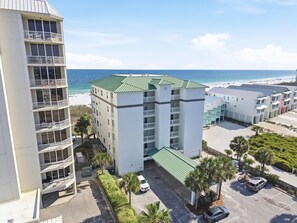 A multi-story hotel with balconies, a parking area, and a view of the beach. - Riviera Dunes 501 (Pensacola)