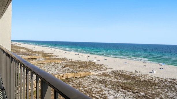 A beach view from a balcony with a wooden railing, sandy beach, and ocean. - Shipwatch D604 (Pensacola)
