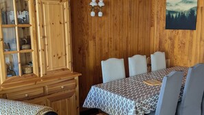 Ein Essbereich mit Holzboden, einem Tisch für vier Personen, einem Schrank mit Glastüren und einem gerahmten Bild an der Wand.