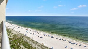 A beach with rows of umbrellas and beach chairs, a clear sky, and the ocean. - Indigo West 1802 (Pensacola)
