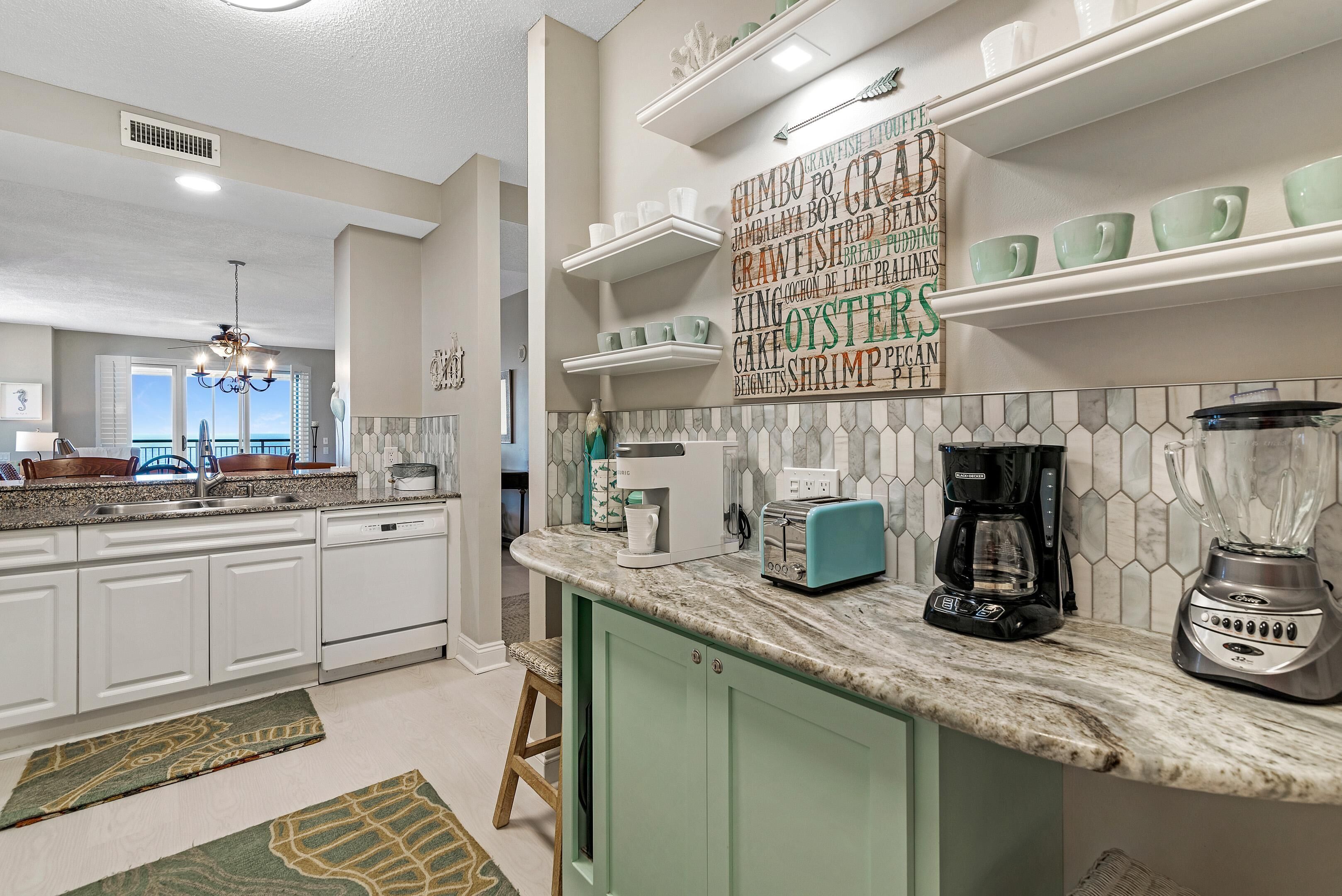 A modern kitchen with white cabinets, a granite countertop, and a view to the outside.