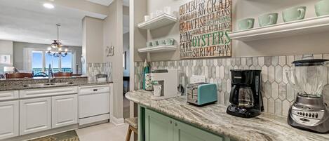 A modern kitchen with white cabinets, a granite countertop, and a view to the outside.