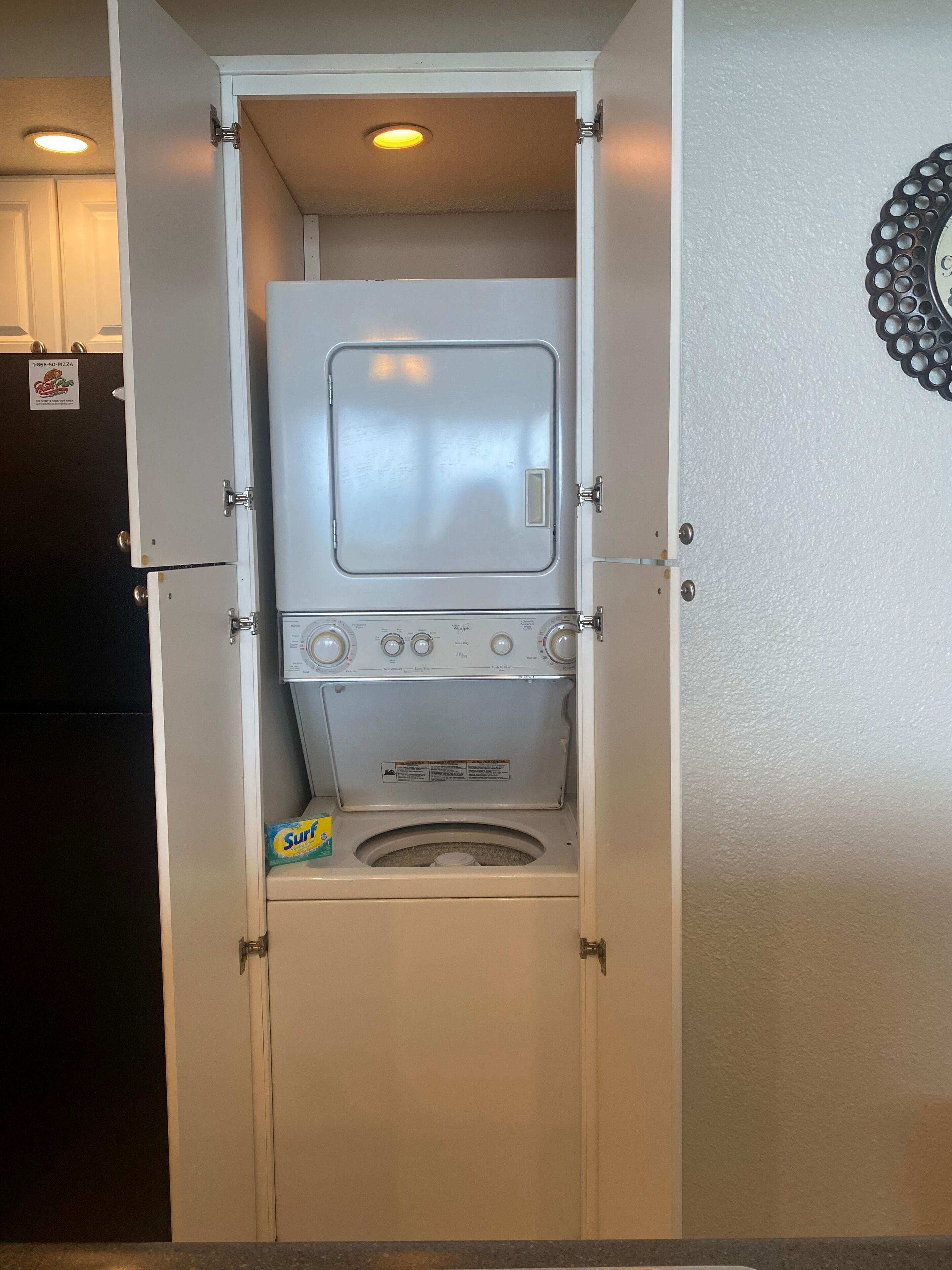 A compact, built-in washer and dryer unit with a control panel, located in a small, enclosed space with a door on one side.