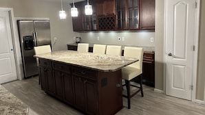 A kitchen with a central island, dark wooden cabinets, and a stainless steel refrigerator. - Quiet & cozy home, bring the whole family. (Monroe Township)