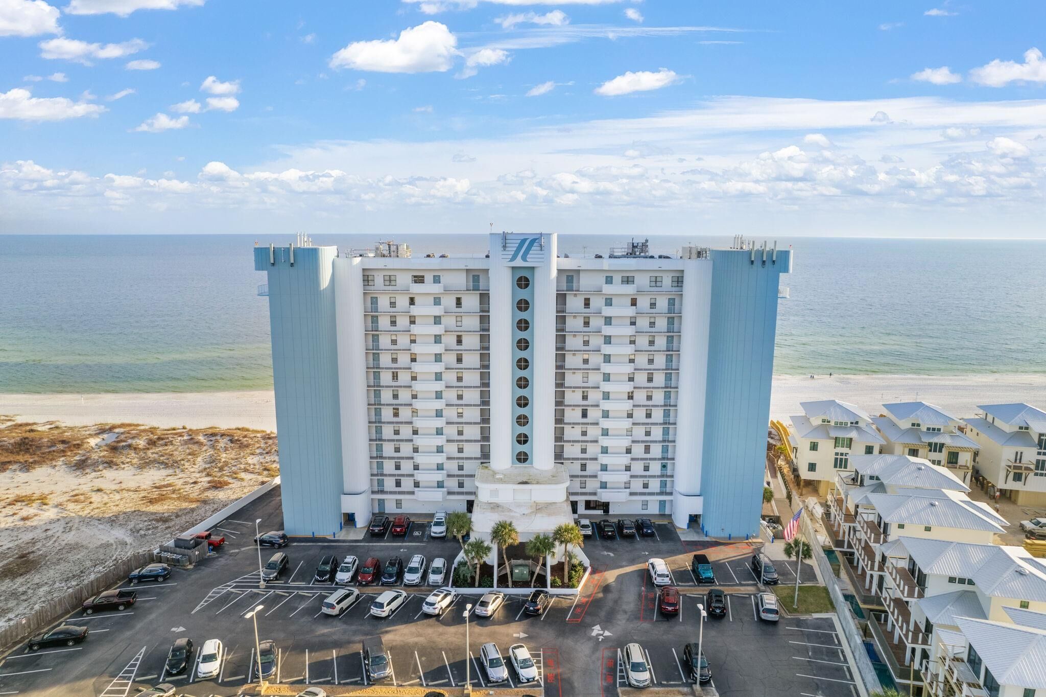 Un hotel moderno con patio central, estacionamiento y vista al océano.