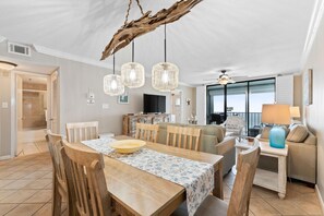 A spacious dining area with a wooden table and chairs, a large bowl, and a ceiling fan. - Summerchase 905 (Orange Beach)