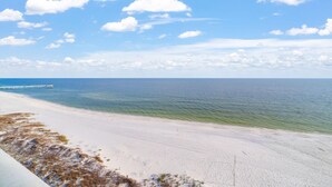 Une plage avec un ciel dégagé et une jetée qui s’avance dans l ’eau.