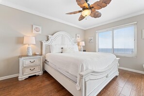 A bedroom with a large bed, white nightstands, a ceiling fan, and a window with blinds. - Summerchase 905 (Orange Beach)