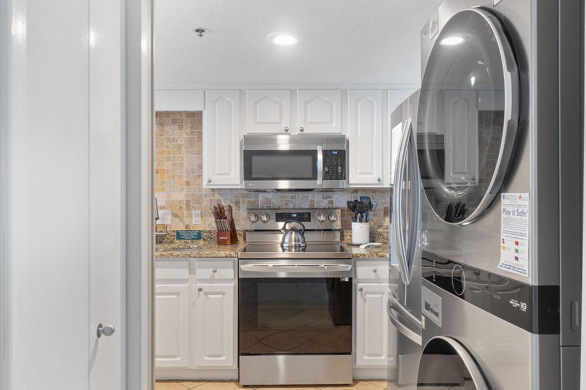 A modern kitchen with white cabinets, a stainless steel microwave, oven, and refrigerator.