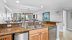 A modern kitchen with granite countertops, stainless steel appliances, and wooden cabinets. - Eden East 101 (Pensacola)