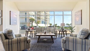 Un salón con sillones a rayas, una mesita de centro y vistas a un edificio de gran altura.