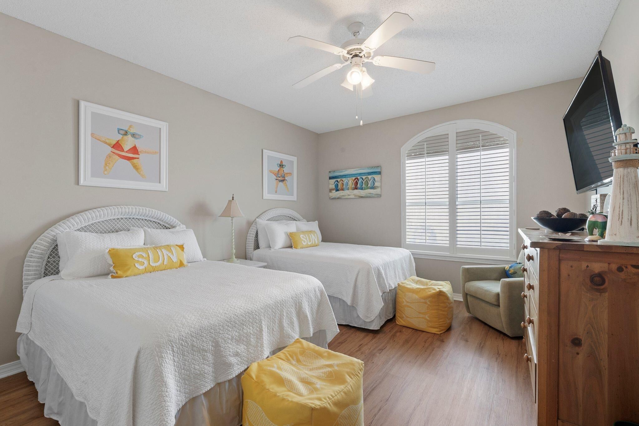 A bedroom with two beds, a ceiling fan, and a window with blinds.
