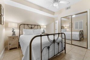 Un dormitorio con cama, mesitas de noche, un espejo y un ventilador de techo.