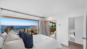 Un ampli dormitori amb un llit gran, un balcó amb una vista panoràmica i una habitació separada amb una porta que dona a l'exterior.