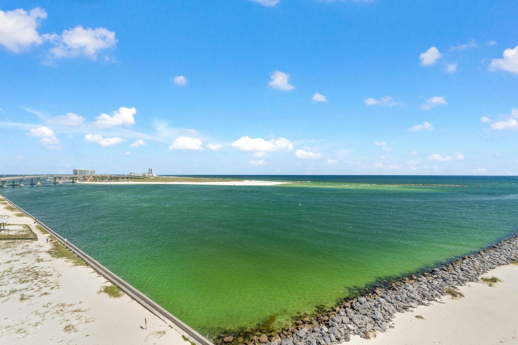 A coastal view with a clear sky, a sandy beach, and a calm sea.