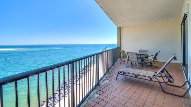 Ein Balkon mit Blick auf das Meer, einem Tisch mit Stühlen und einem gefliesten Boden.