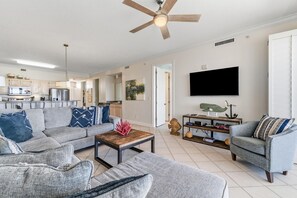 A modern living room with a sofa, armchairs, a coffee table, and a TV mounted on the wall. - Grand Pointe 702 (Orange Beach)