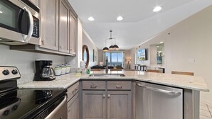 A modern kitchen with a built-in oven, microwave, and stainless steel dishwasher. - Enclave 506 (Orange Beach)