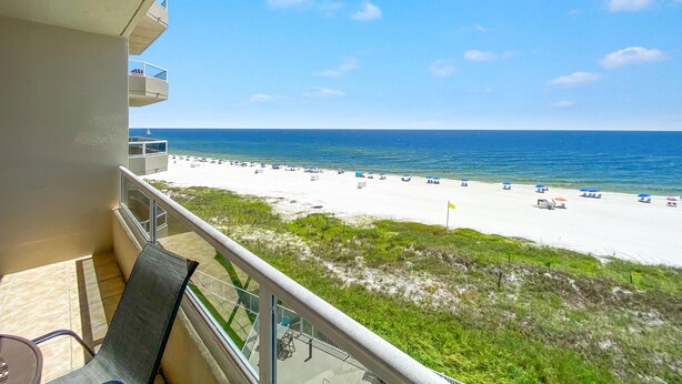 A balcony with a view of a beach, a pool, and a clear blue sky. - Enclave 506 (Orange Beach)