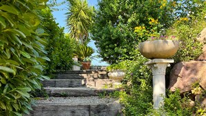 A stone staircase surrounded by lush greenery and a large stone planter. - Double Family Villa,12 people with Pool near Cannes (Fréjus)