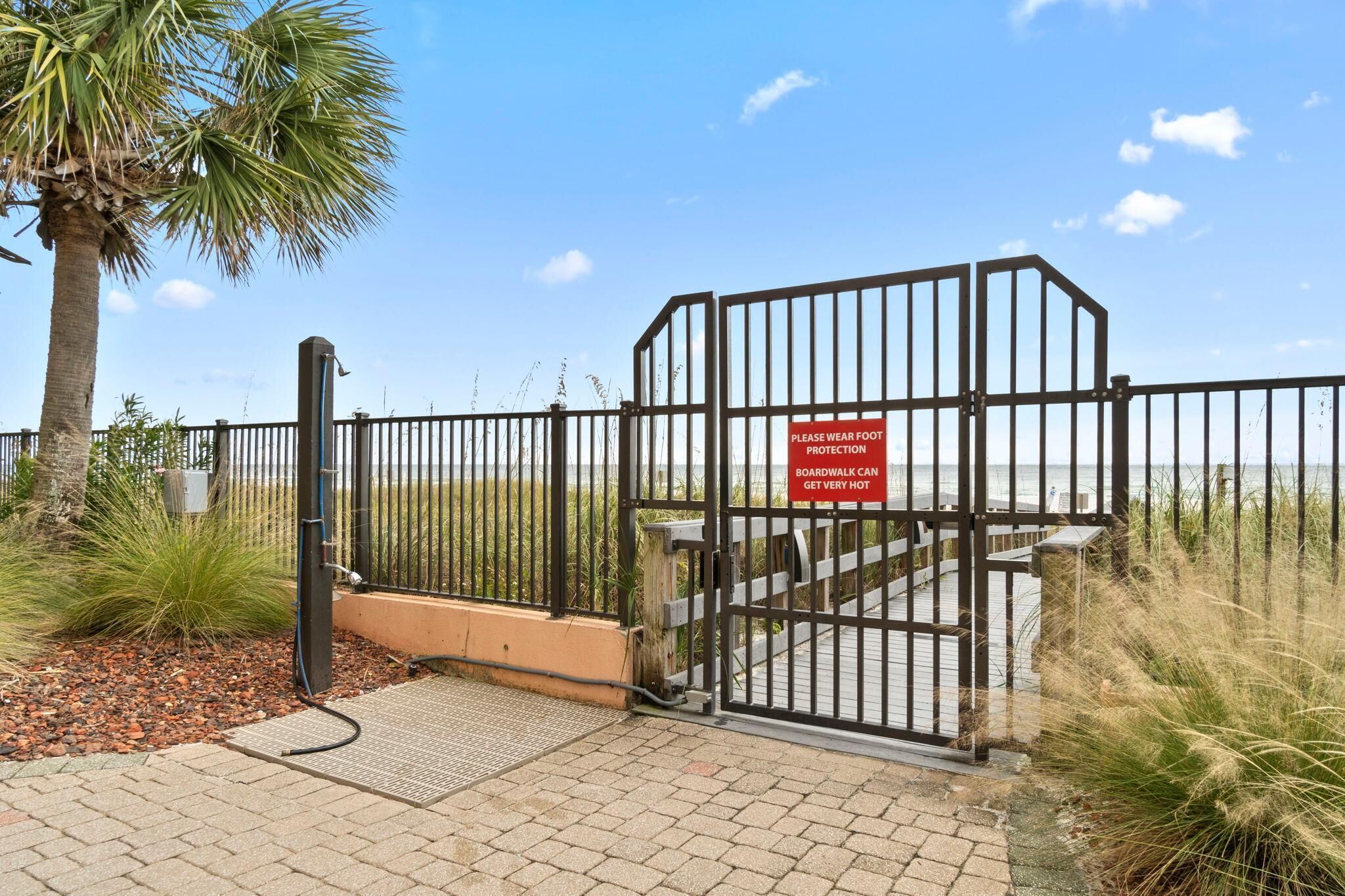 A gated entrance with a sign warning of hot pavement.