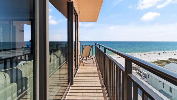 A balcony with a view of the beach, a chair, and a railing. - Seachase 905w (Orange Beach)