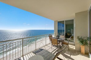 Ein Balkon mit Blick auf das Meer, einem Esstisch, Stühlen und einer Topfpflanze.