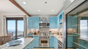 A modern kitchen with blue cabinets, stainless steel appliances, and a large island. - Phoenix VII 1401 (Orange Beach)