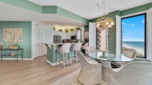 A modern kitchen with white cabinets, a glass island, and a view of the beach.