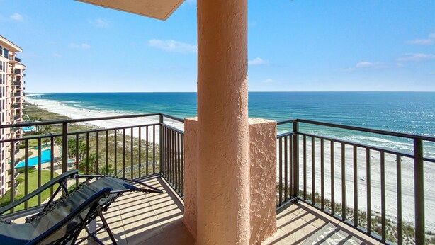 A balcony with a view of the beach and ocean.
