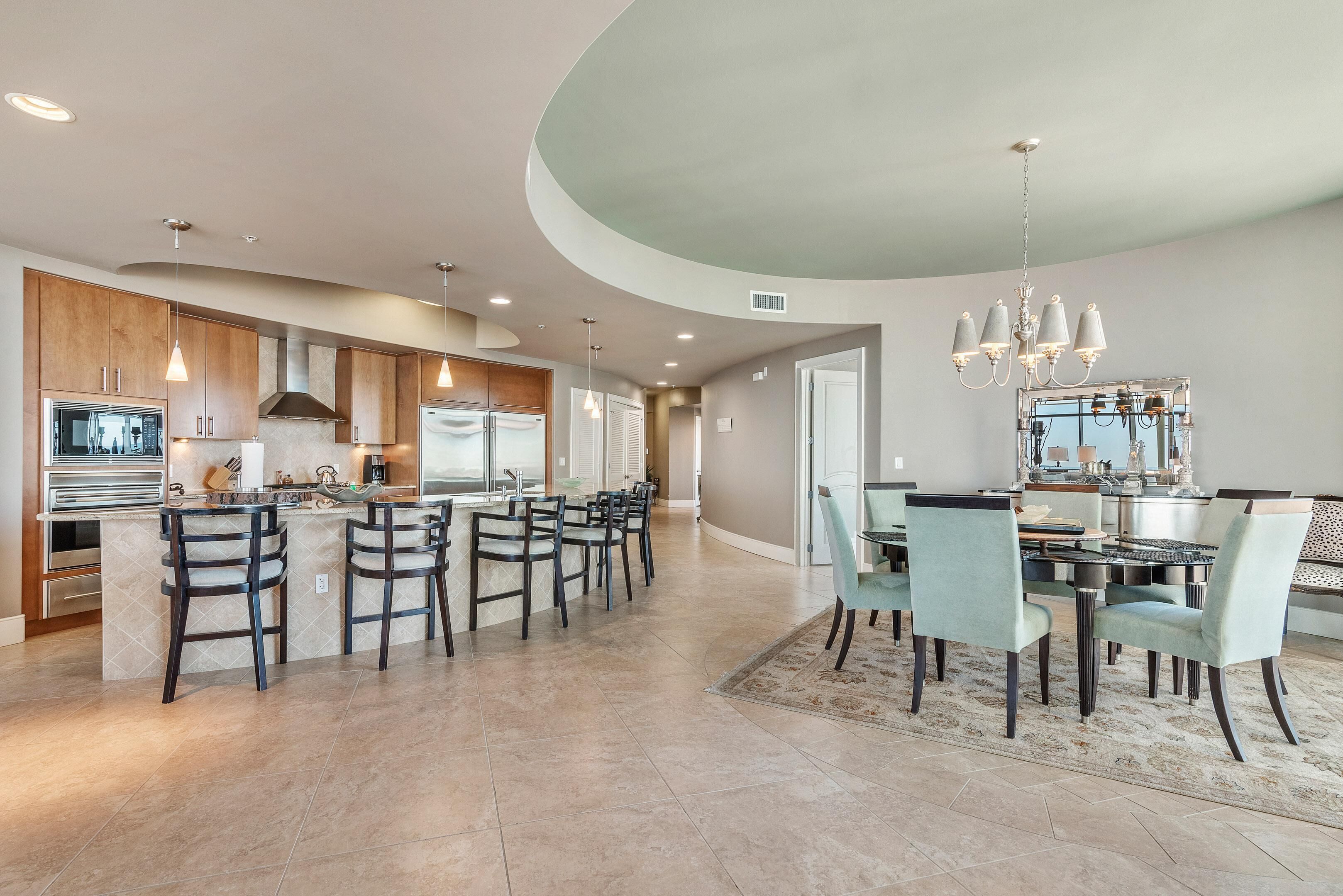 A spacious kitchen with a central island, dark wooden cabinets, and modern appliances.
