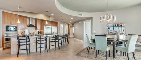 A spacious kitchen with a central island, dark wooden cabinets, and modern appliances.