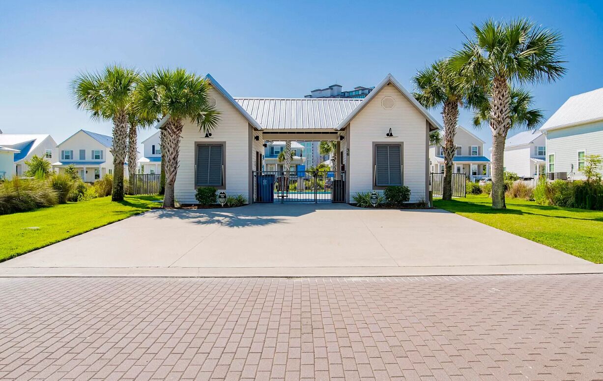 A gated entrance to a residential complex with a paved walkway leading to the entrance.