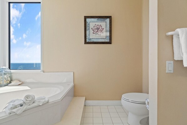 A bathroom with a bathtub, toilet, and a framed picture on the wall. - Beach Colony Tower Penthouse 17C (Pensacola)