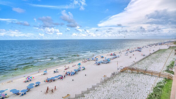 A beach with umbrellas, chairs, and a wooden walkway along the shore. - Sandy Key 713 (Pensacola)