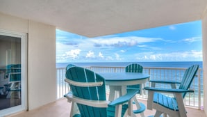 A balcony with a view of the ocean, featuring teal Adirondack chairs and a small table. - Sandy Key 713 (Pensacola)